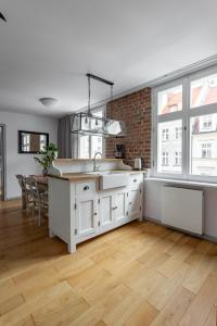 a kitchen with white cabinets and a brick wall at Klimatyczne mieszkanie w centrum in Poznań
