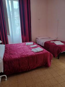 two beds with red sheets in a room with a window at B&B Appartamenti Napoli in Naples