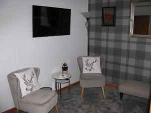 a living room with two chairs and a table and a tv at Fairfield Townhouse Guest House Selfcatering in Inverness
