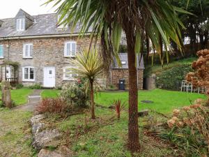 a stone house with palm trees in front of it at Lanvean Farmhouse in Newquay