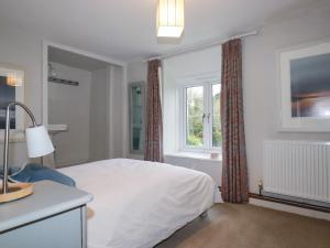 a bedroom with a white bed and a window at Lanvean Farmhouse in Newquay