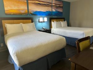 a hotel room with two beds and a table at Days Inn & Suites by Wyndham Tampa - Ybor City in Tampa
