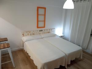 1 dormitorio con 1 cama blanca y 1 silla en Pelamios Catedral, en Santiago de Compostela
