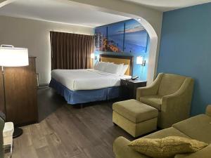 坦帕的住宿－Days Inn & Suites by Wyndham Tampa - Ybor City，配有一张床和一把椅子的酒店客房