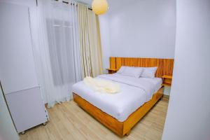 a bedroom with a bed with white sheets and a window at Makeri Residence - Musanze , Rwanda in Ruhengeri