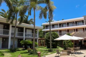 ośrodek z palmami, krzesłami i parasolem w obiekcie Hotel Coral Beach w mieście Tamandaré