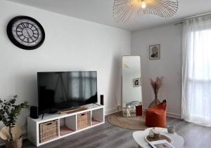 ein Wohnzimmer mit einem TV und einer Uhr an der Wand in der Unterkunft Europe in Montargis