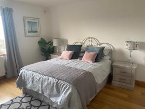 1 dormitorio con 1 cama con almohadas rosas y grises en Highmains en Dumfries