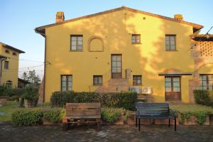a yellow house with two benches in front of it at Tenuta Il Casale di San Miniato in San Miniato