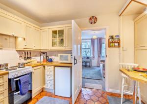 a kitchen with white cabinets and a white refrigerator at Gardenwell Cottage in Hawes