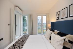 um quarto com uma grande cama branca e 2 janelas em The Wembley Park Gem - Lovely 2BDR Flat with Balcony em Londres