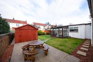 a backyard with a picnic table and a shed at The Prestwick Pad in Prestwick
