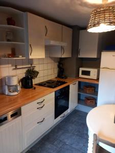 Lierneux的住宿－Le fournil，厨房配有白色橱柜和炉灶烤箱。