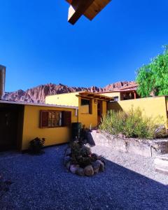 a yellow house with a mountain in the background at Retama in Tilcara
