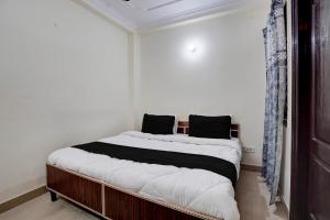 a bedroom with a bed with white sheets and black pillows at Hotel O Peaceful Paradise in New Delhi