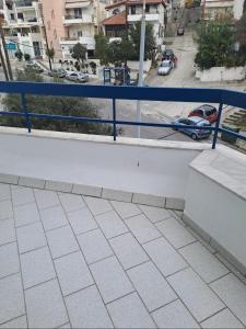 uma varanda com um corrimão azul e um carro numa rua em Spitaki em Kavala