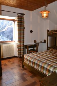 um quarto com uma cama, uma mesa e uma janela em ALBERGO VALLUNGA em Tartano