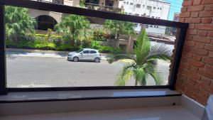 a window with a view of a palm tree at Atlantica Suites in Guarujá