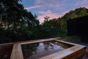bañera de hidromasaje en una terraza de madera con árboles en 奥武雄温泉　風の森 en Ureshino