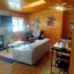 uma sala de estar com um sofá branco e uma cadeira em Cabin on the lake, and trails! em Birchwood