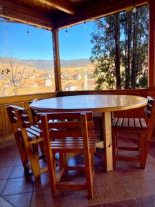 uma mesa de madeira e cadeiras num alpendre com uma janela em Pensiunea Casa-Stefanel em Sadova