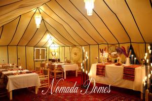 a tent with tables and chairs and lights in it at Nomada Domes in Merzouga