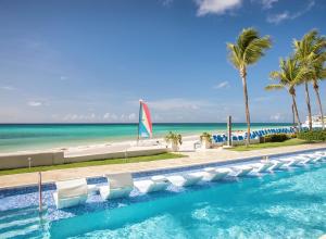 a swimming pool with chairs and the beach at Sea Breeze Beach House All Inclusive by Ocean Hotels in Christ Church