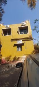 um carro passando por um edifício amarelo com janelas em Chaitra Home Hampi em New Hampi