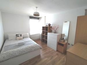 a white bedroom with a bed and a mirror at Stylish flat in London, Canary Wharf in London