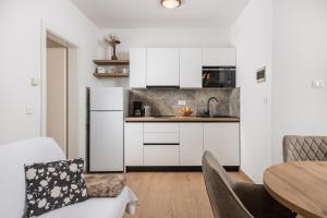 a kitchen with white cabinets and a table and chairs at Guest House Marica in Rovinj