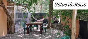 einen Tisch und Stühle in einem Garten mit einem Schild in der Unterkunft Gotas de Rocio in Piriápolis