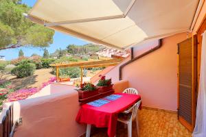 a red table and chairs on a balcony with a view at Cala Rossa Pool & Nature - Goelba in Nisporto