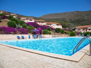 a large swimming pool with blue water in a resort at Cala Rossa Pool & Nature - Goelba in Nisporto