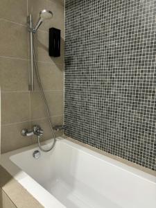 a white bath tub with a shower in a bathroom at The Ooak Suites by Bamboo Hospitality in Kuala Lumpur