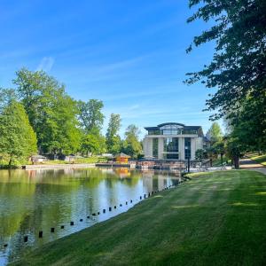 a building next to a lake in a park at Le Forges Hotel in Forges-les-Eaux