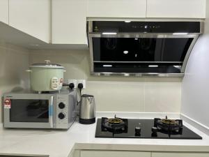 a kitchen with a microwave and a stove top oven at The Ooak Suites, Kiara 163 by Bamboo Hospitality in Kuala Lumpur