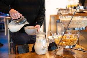 a person pouring milk into a bowl on a counter at St Christopher's Inn Camden in London