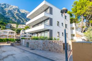 a white building with mountains in the background at Apartmani Pino 1 in Baška Voda