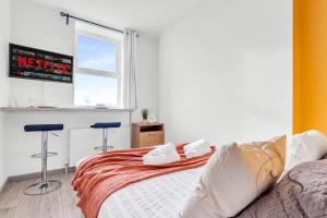 a bedroom with a bed and a window and two stools at Gorgeous Longton Studio 2b in Stoke on Trent