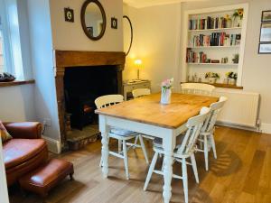 a dining room table with chairs and a fireplace at Adlington Cottage, Lancashire in Adlington