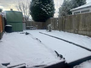 een tuin bedekt met sneeuw met een hek bij Charming 2-Bedroom Home with Modern Amenities in Oldham