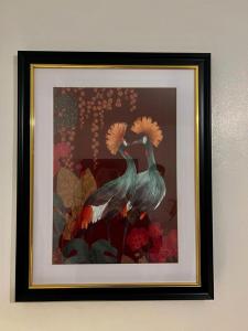 a framed picture of two peacocks on a wall at Charming 2-Bedroom Home with Modern Amenities in Oldham