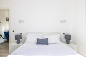 una camera da letto con un letto bianco con cuscini bianchi di Maison Blu - in Trastevere a Roma