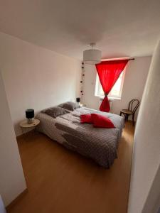 1 dormitorio con 1 cama con cortina roja y ventana en Jolie maison de campagne, Compostelle en Soleymieux