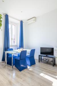 una sala da pranzo con sedie blu, tavolo e TV di Maison Blu - in Trastevere a Roma