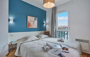 サン・ジャン・ド・リュズにあるRésidence Odalys Domaine Iratziaの青い壁の客室で、ベッド2台、窓が備わります。