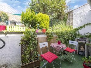 einen kleinen Garten mit einem Tisch, Stühlen und einem Zaun in der Unterkunft La Marquisienne avec jardin in Marquise