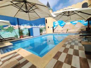 una piscina con due ombrelloni e un pavimento a scacchiera di Hotel Villa a San Juan del Paraná
