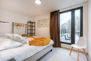 een slaapkamer met een bed, een stoel en een raam bij Apartment with two large terraces in Zedelgem