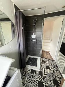 y baño con ducha y azulejos blancos y negros. en Jolie maison de campagne, Compostelle, en Soleymieux